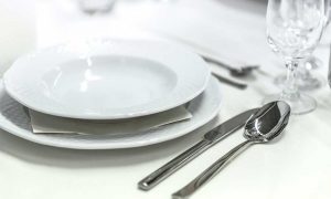 A place setting with a spoon, knife, glass, and plate
