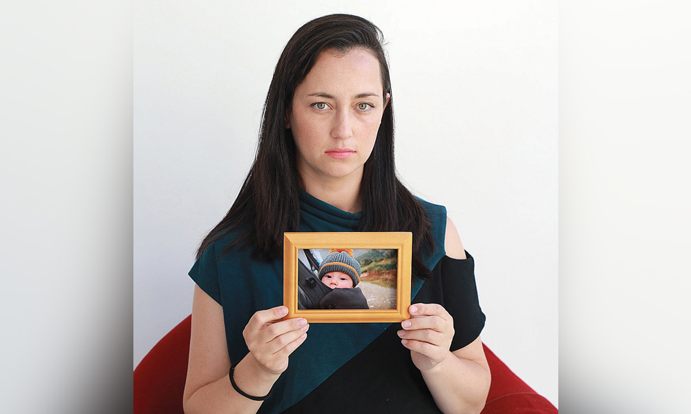 Anat Dayagi, founder of Parents for Infant Care, poses with a photo of her late child.