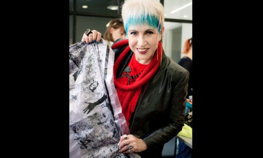 a woman holds up a piece of fabric.