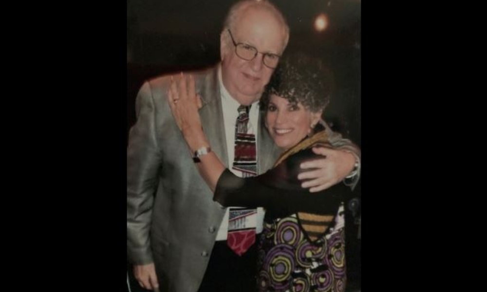 an old man and woman hug and smile for the camera