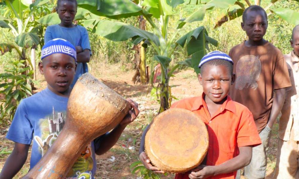 Abayudaya children holding drums while wearing kippot