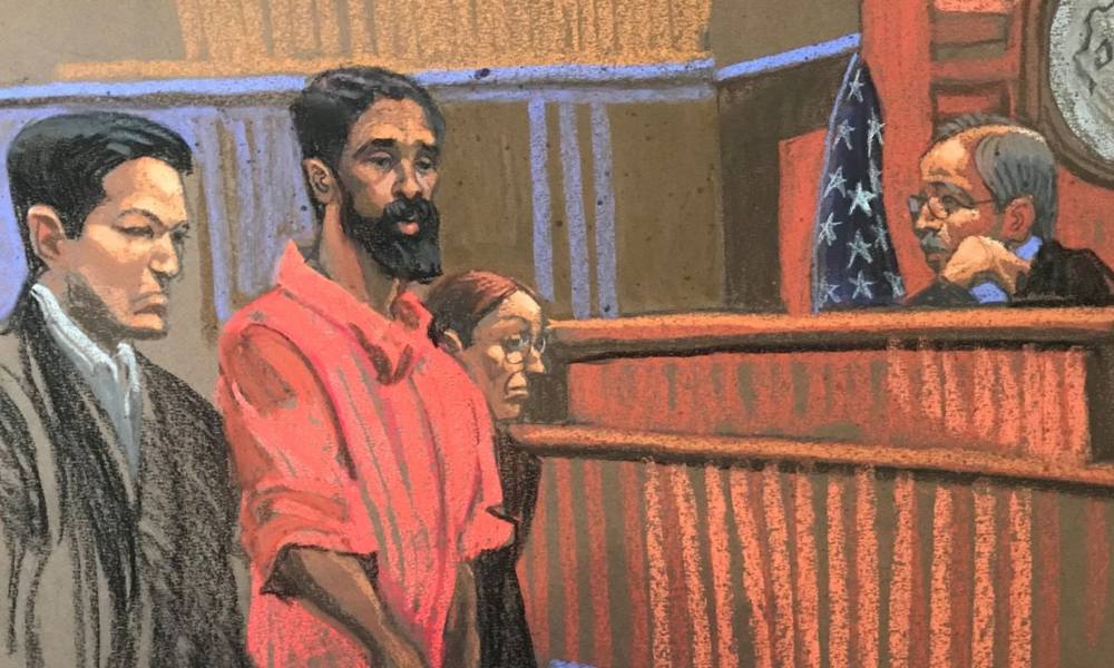 A courtroom sketch. A tall bearded black man stands in an orange jumpsuit in a courtroom, with a suited man to his right and a woman to his left. On the right side of the image, a judge is seated.