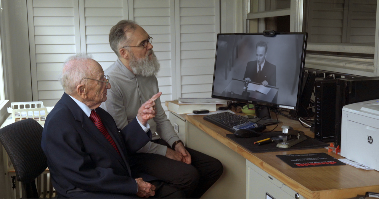 102-year-old Benjamin Ferencz pointing to a WWII-era video of himself on a computer