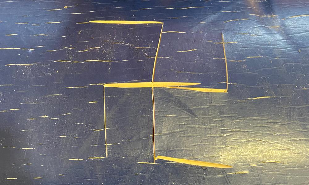 A swastika carved into a blue wooden school desk. From the ADL's 2022 audit.