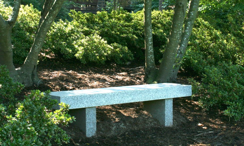 A stone bench between trees.