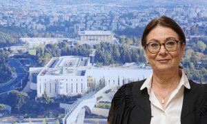A woman with brown hair, black glasses, a white shirt, and a black robe in front of the Israeli Supreme Court building.