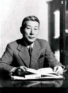 A black and white portrait of a Japanese official in suit and tie. 