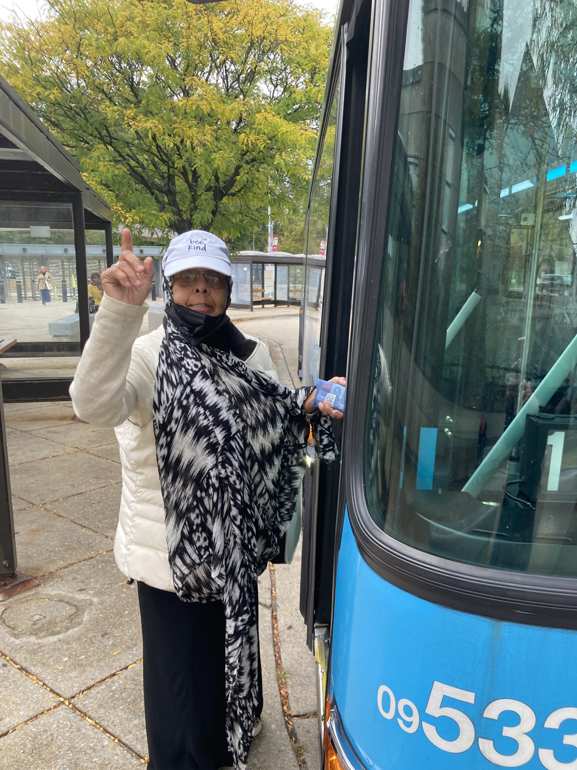 A smiling woman gets onto a bus.