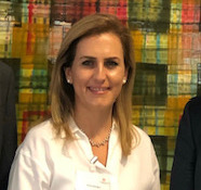 A smiling woman with white hearings and a white shirt.