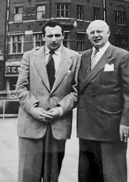 A black and white photo of two men in suits standing next to each other.