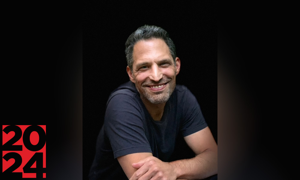 Smiling man with short salt and pepper hair and a goatee wearing a black T-shirt