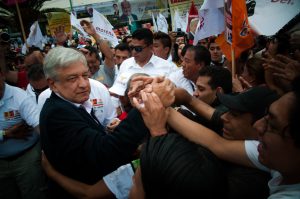 Older man in the middle of a crowd who grasp his hand.