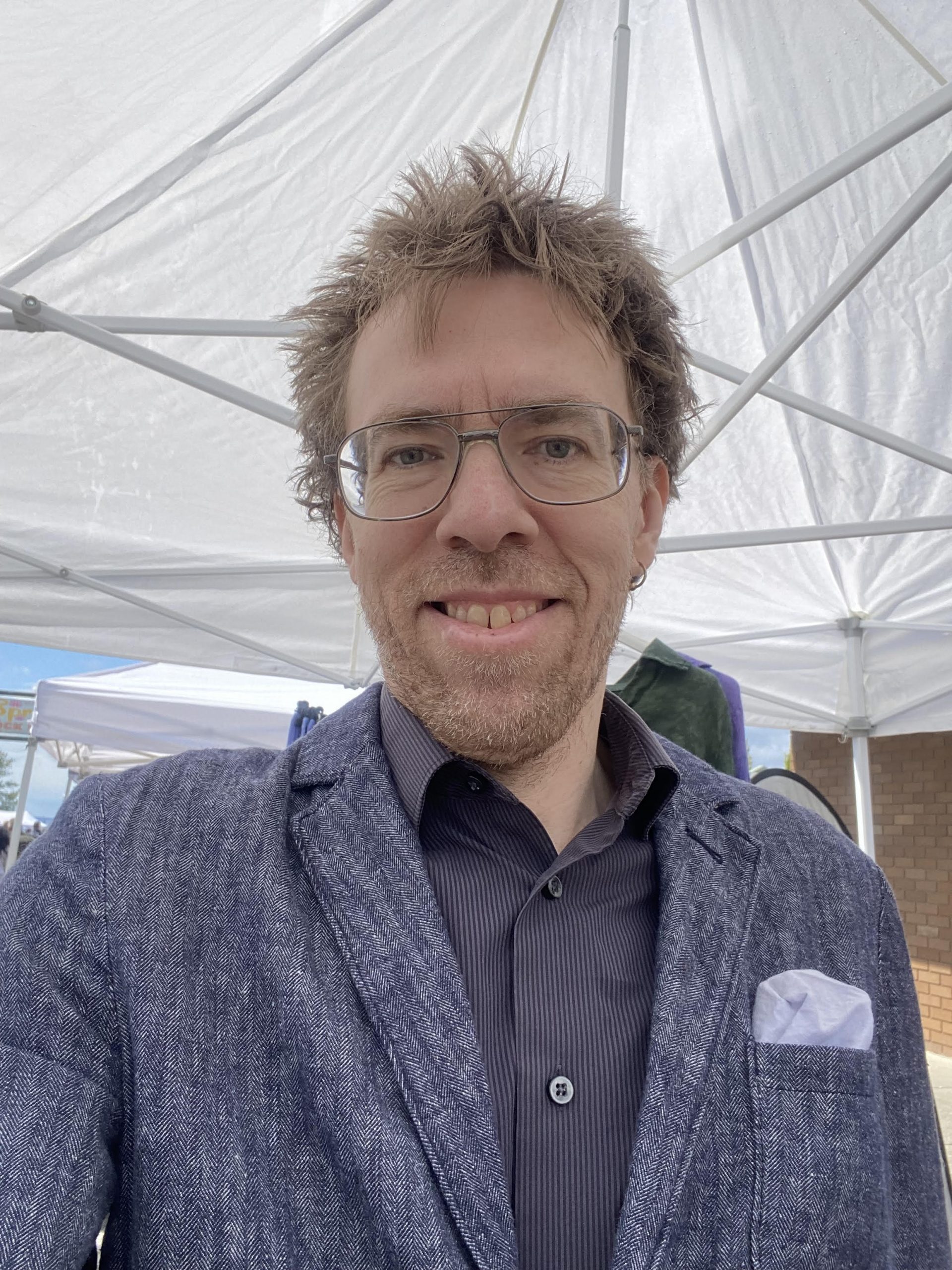 A white man in a blue jacket and shirt smiles at the camera.