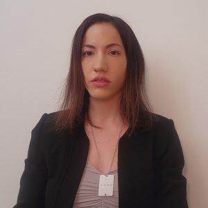 Young woman with straight brown hair, in a black blazer.