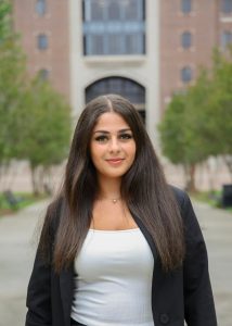 Young woman with long dark hair in a black blazer.