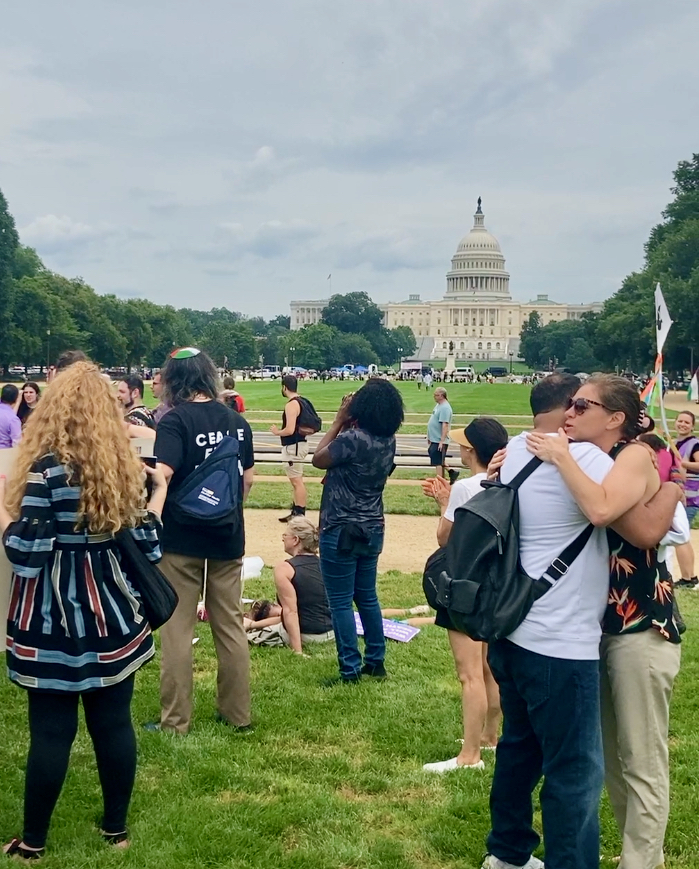 Protesters hug against the backdrop of the Capitol Building.
