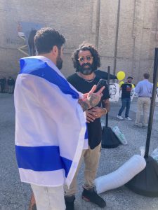 Tomer Peretz talks to a man in Israeli flag