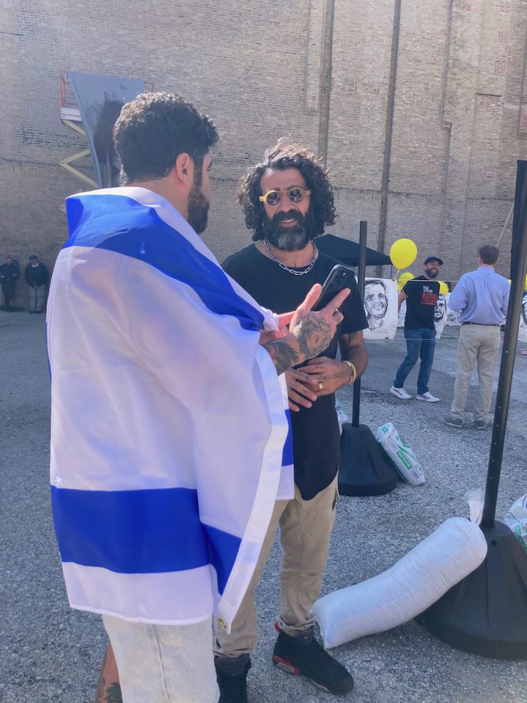 Tomer Peretz talks to a man in Israeli flag