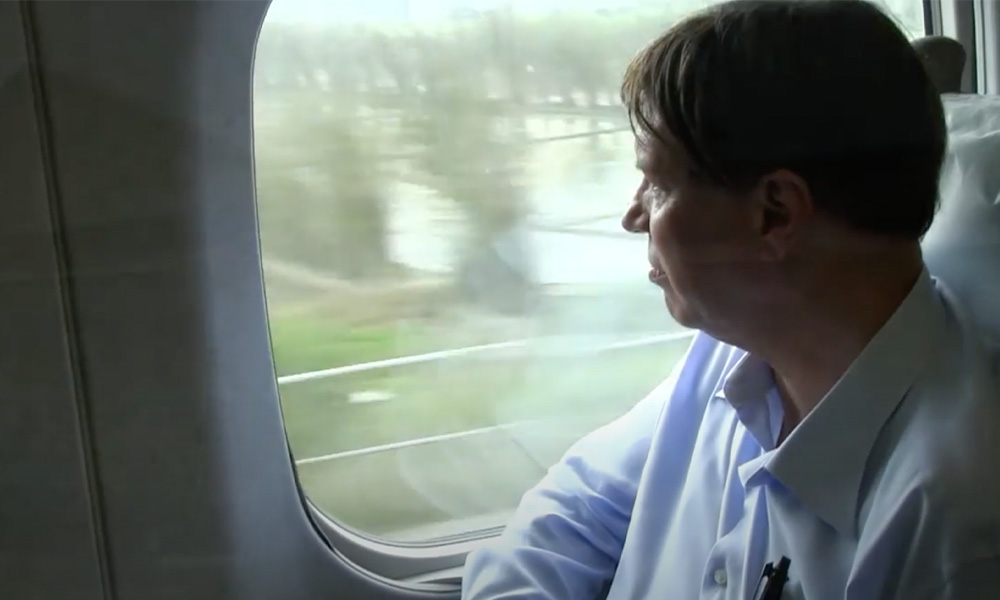 Hideo Levy looking out the window of a moving train